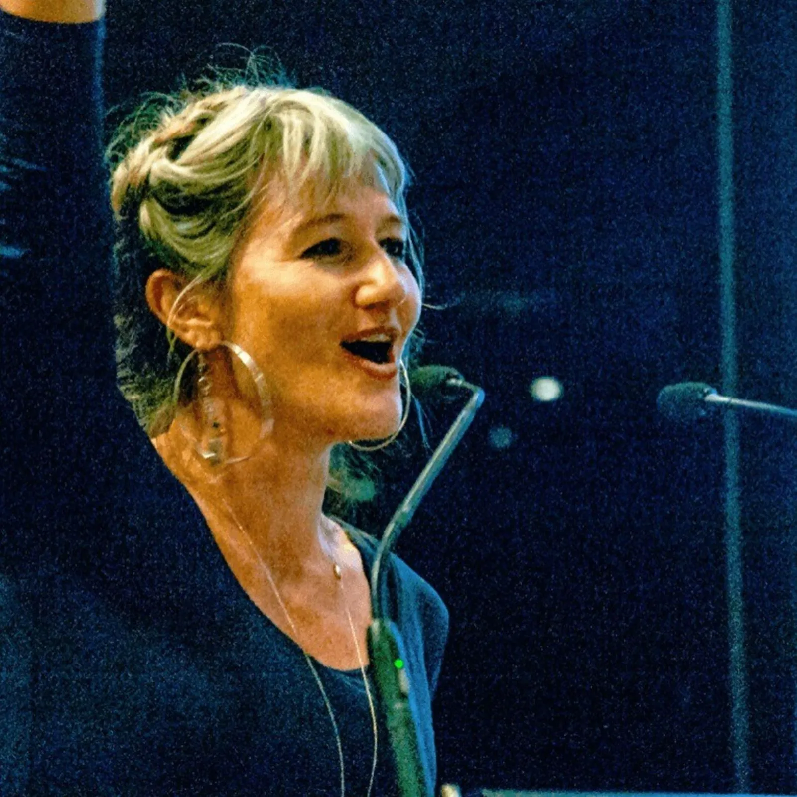 Alex Sangster speaking into a microphone with one arm raised.